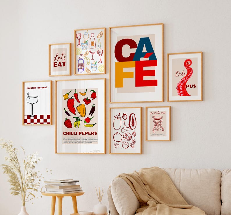 May include: A collection of eight framed prints with various designs. The prints feature colorful illustrations of cocktails, food, and text. The prints are arranged in a grid pattern on a white wall.