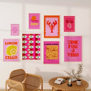 May include: A collection of eight colorful wall art prints with various designs, including a lemon, a lobster, flowers, and text. The prints are framed in wood and have a pink background.