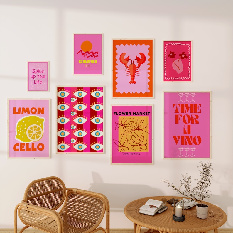 May include: A collection of eight colorful wall art prints with various designs, including a lemon, a lobster, flowers, and text. The prints are framed in wood and have a pink background.