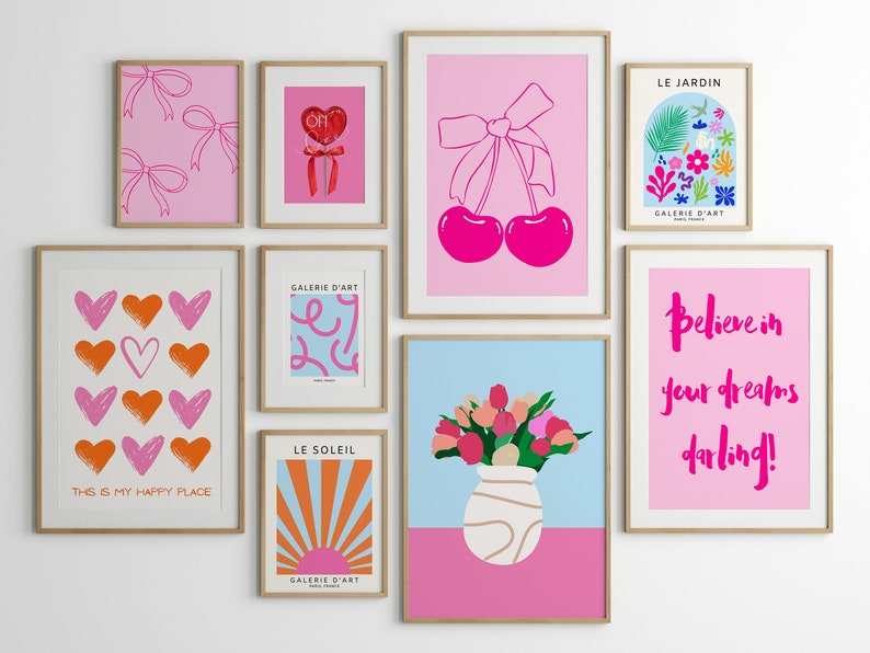 May include: A gallery wall with nine framed prints featuring various designs. The prints include hearts, cherries, flowers, a sun, and text. The prints are all in pink, orange, red, blue, and white.