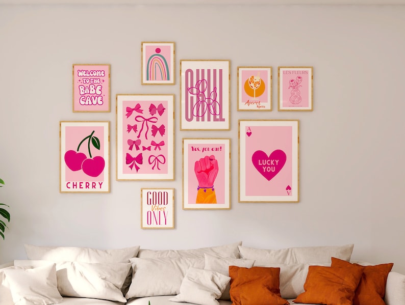 May include: A wall gallery featuring nine framed prints with pink and white designs. The prints include text such as "Welcome to the Babe Cave", "Cherry", "Good Vibes Only", "Yes, you can!" and "Lucky You".