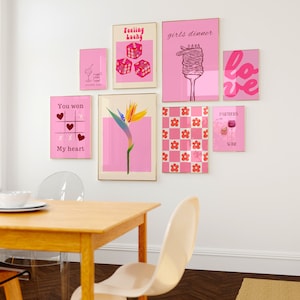 May include: A collection of eight pink and white framed prints with various designs, including dice, a flower, a heart, a glass of wine, and the words "Feeling Lucky", "Girls Dinner", "Love", "You Won", "My Heart", and "Partners in Wine".