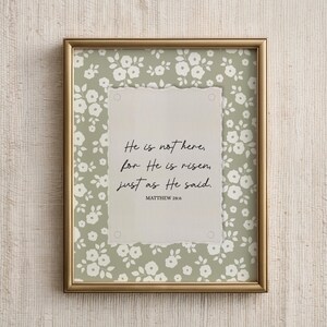 Pu&ograve; includere: Una stampa incorniciata con una cornice color oro. La stampa presenta uno sfondo a motivi floreali verde chiaro e una carta dai bordi strappati con il testo "He is not here, for He is risen, just as He said. Matthew 28:6."
