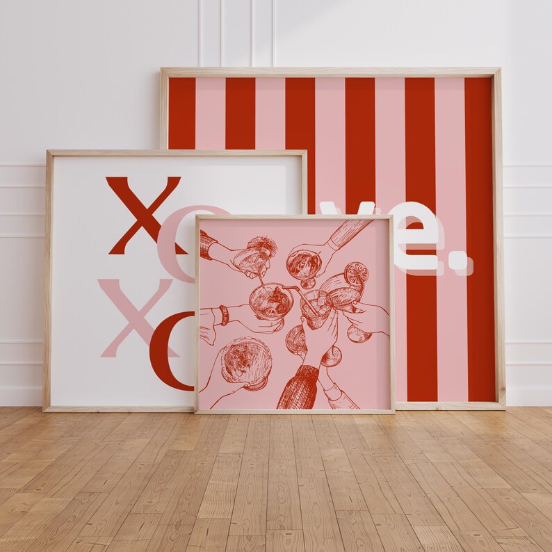 May include: Three framed prints with a pink and red striped pattern, the word "XO" in red, and a drawing of hands holding up glasses of drinks. The text "we" is visible on the striped print.