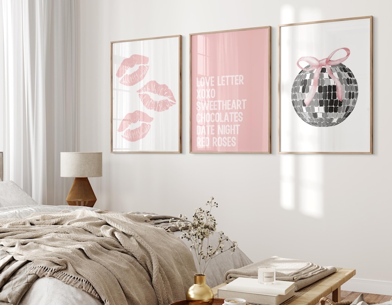 May include: Three framed prints with pink backgrounds. The left print features three pink lips, the middle print has the text "Love Letter XOXO Sweetheart Chocolates Date Night Red Roses", and the right print shows a silver disco ball with a pink ribbon.
