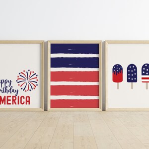 Pu&ograve; includere: Tre stampe incorniciate con un tema patriottico. La prima stampa presenta il testo "happy birthday AMERICA" con una grafica di fuochi d'artificio rosso, bianco e blu. La seconda stampa presenta strisce rosse e blu. La terza stampa presenta tre ghiaccioli con disegni rosso, bianco e blu.