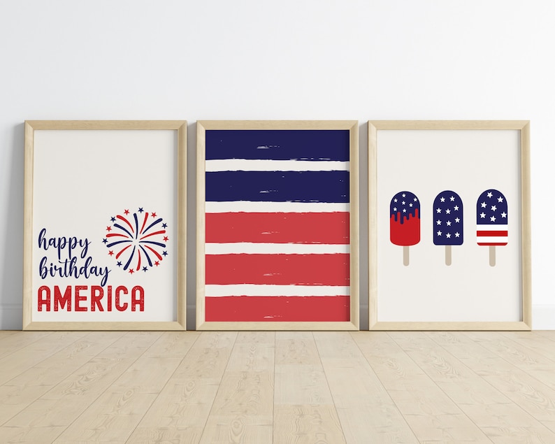 Pu&ograve; includere: Tre stampe incorniciate con un tema patriottico. La prima stampa presenta il testo "happy birthday AMERICA" con una grafica di fuochi d'artificio rosso, bianco e blu. La seconda stampa presenta strisce rosse e blu. La terza stampa presenta tre ghiaccioli con disegni rosso, bianco e blu.