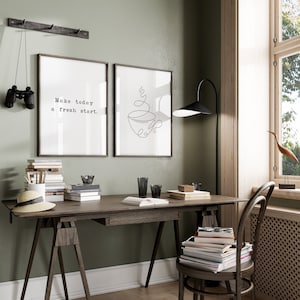 May include: A home office setup featuring a wooden desk, chair, and a floor lamp. Two framed prints adorn the wall, one with the text "Make today a fresh start." and the other a line drawing of a coffee cup. Binoculars hang on the wall.