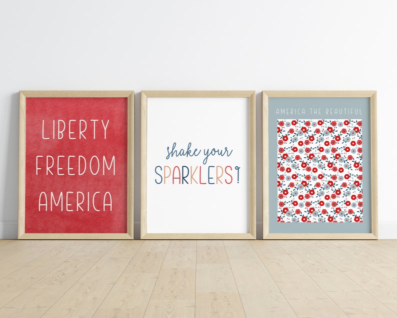 Pu&ograve; includere: Tre stampe incorniciate con temi patriottici. La stampa a sinistra ha uno sfondo rosso con le parole "Libert&agrave;, Libert&agrave;, America" in bianco. La stampa al centro ha uno sfondo bianco con le parole "Scuoti i tuoi fuochi d'artificio!" in blu, rosso e arancione. La stampa a destra ha uno sfondo blu con un motivo floreale rosso e bianco e le parole "America la Bella" in alto.