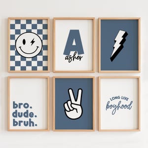 May include: Set of six blue and white framed prints with various designs, including a smiley face with a lightning bolt, the letter A with the name Asher, a lightning bolt, the words "bro. dude. bruh.", a peace sign, and the words "Long Live Boyhood".
