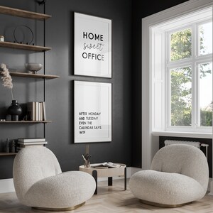 May include: Interior shot of a home office with two framed prints on a dark grey wall. One print reads "HOME sweet OFFICE," and the other says "AFTER MONDAY AND TUESDAY EVEN THE CALENDAR SAYS WTF." Two cream-coloured, rounded armchairs sit on a wood floor.