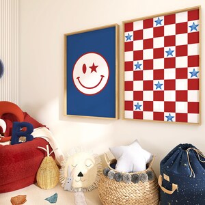 May include: Two framed wall art pieces. One features a blue background with a white smiley face and a star. The other has a red and white checkerboard pattern with blue stars. A red beanbag chair, a blue clock, and decorative items complete the room.