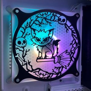 May include: A black and white computer fan cover with a Halloween theme. The design features a cat riding a broomstick with a skull and branches in the background. The fan cover is illuminated with blue and purple lights.