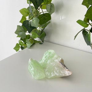 May include: Three pieces of green selenite crystal, with a light green color and a white, translucent appearance. The crystals are rough and have a natural, unpolished look.
