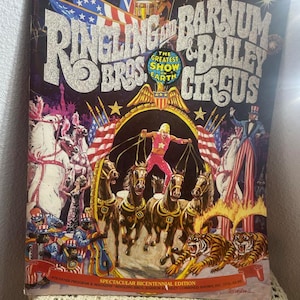 May include: A vintage Ringling Bros. and Barnum & Bailey Circus souvenir program and magazine from 1975. The cover features a colorful illustration of a circus parade with horses, tigers, and a performer on a trapeze. The text on the cover reads "Ringling Bros. and Barnum & Bailey Circus, The Greatest Show on Earth, Spectacular Bicentennial Edition, Souvenir Program & Magazine, Ringling Bros. Barnum & Bailey Combined Shows, Inc. 1975, $12.00."