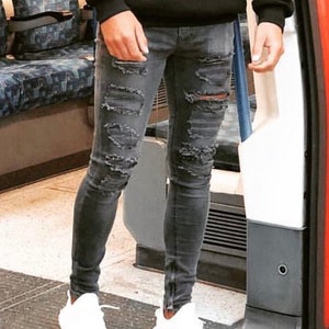 May include: A person wearing gray distressed skinny jeans with zipper details and white sneakers.
