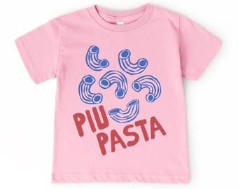 Puede incluir: Camiseta rosa claro con un diseño lúdico de formas de pasta azules y blancas. Las palabras "PIU PASTA" están impresas en rojo debajo. La camiseta está hecha de un material suave.