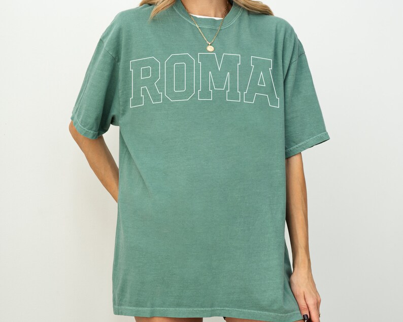 May include: A green oversized t-shirt with the word "ROMA" printed in white on the front.