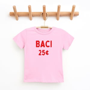 May include: A pink t-shirt with the words "BACI 25&cent;" printed in red on the front.