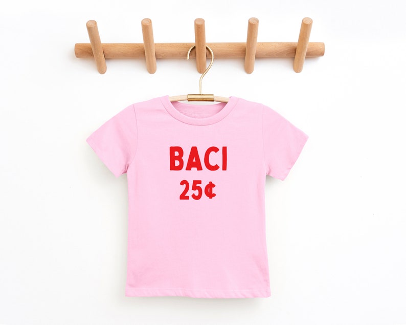 May include: A pink t-shirt with the words "BACI 25&cent;" printed in red on the front.