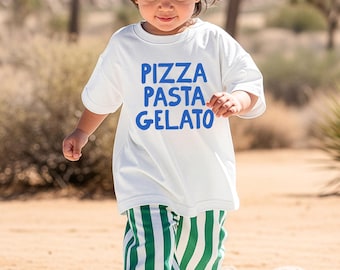 May include: A white short-sleeved t-shirt with the blue text PIZZA PASTA GELATO printed on the front, paired with green and white vertically striped pants and light-colored sneakers. The outfit features a casual design with a crew neckline.