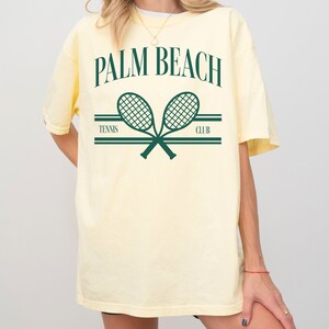 May include: A yellow t-shirt with a graphic print of two crossed tennis rackets and the text "PALM BEACH TENNIS CLUB".
