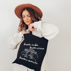 May include: A black tote bag with white text that reads "buon cibo buon vino buoni amici" and a graphic of three wine glasses clinking.