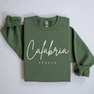 May include: A green sweatshirt with the text "Calabria ITALIA" in white cursive lettering.