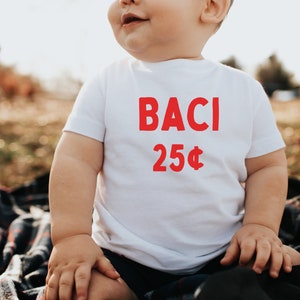 May include: A white t-shirt with the words "BACI 25&cent;" printed in red.