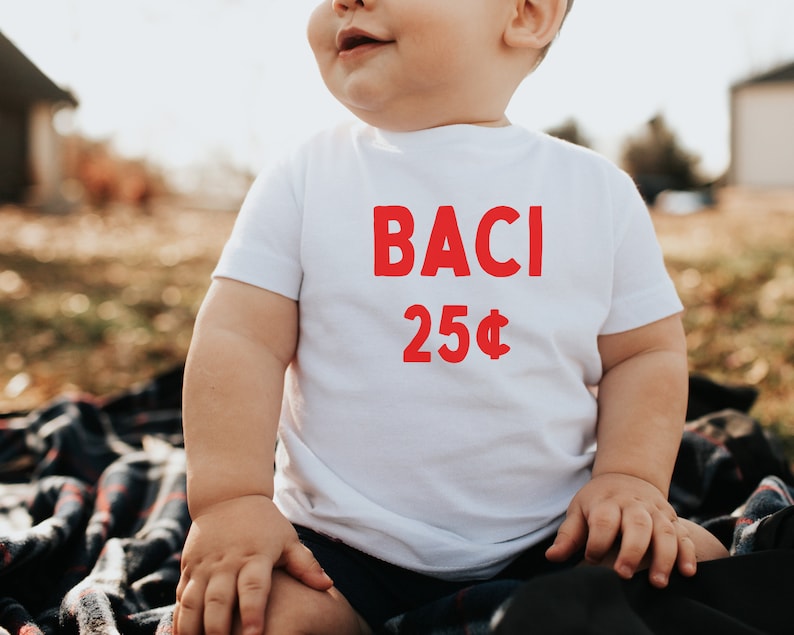 May include: A white t-shirt with the words "BACI 25&cent;" printed in red.