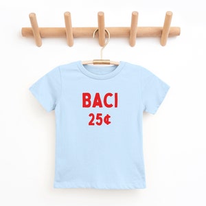 May include: A light blue t-shirt with the words "BACI 25&cent;" printed in red.
