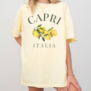 May include: A yellow t-shirt with a graphic print of lemons and green leaves. The text "CAPRI ITALIA" is printed on the shirt.
