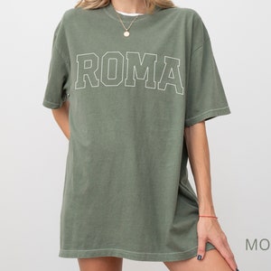 May include: A green oversized t-shirt with the word "ROMA" printed in white on the front.
