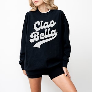 Puede incluir: Sudadera negra con un gr&aacute;fico blanco de estilo retro que dice "Ciao Bella".