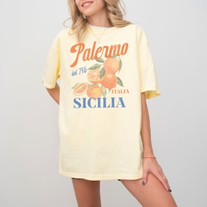May include: A yellow t-shirt with a graphic print of oranges and the text "Palermo dal 745 ITALIA SICILIA".