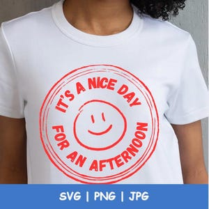 May include: White t-shirt with a red circular graphic that reads "It's a nice day for an afternoon" around a smiling face. The bottom of the image shows the text "SVG | PNG | JPG".