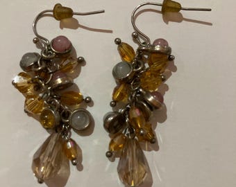 May include: A pair of dangle earrings with silver-tone hooks. Each earring features a cluster of small, colorful beads in shades of yellow, orange, pink, and gray, with teardrop-shaped crystal pendants.