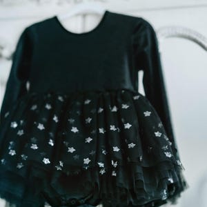 Detailed shot of black velvet long-sleeve bodysuit with layered star-sparkle tulle tutu.