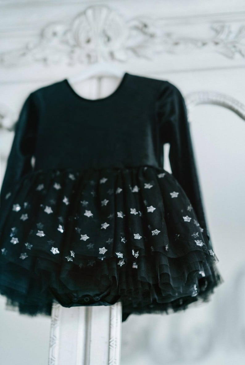 Detailed shot of black velvet long-sleeve bodysuit with layered star-sparkle tulle tutu.