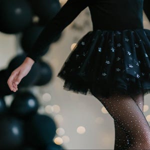 Child twirling in a midnight velvet tutu bodysuit with star sparkle tulle.