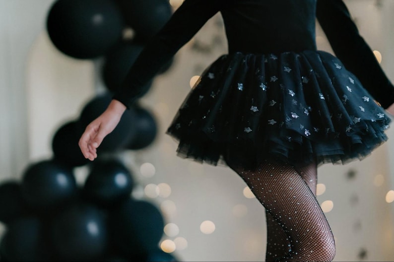Child twirling in a midnight velvet tutu bodysuit with star sparkle tulle.