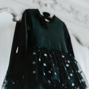 Black velvet tutu bodysuit with starry skirt hanging in soft studio lighting.