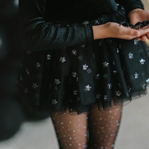 Macro shot of star-patterned tulle layered over a black velvet bodysuit.