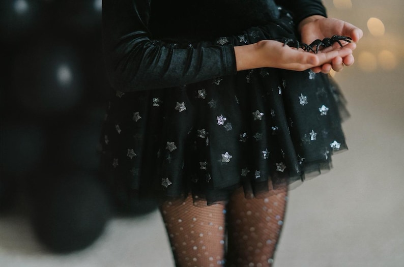 Macro shot of star-patterned tulle layered over a black velvet bodysuit.