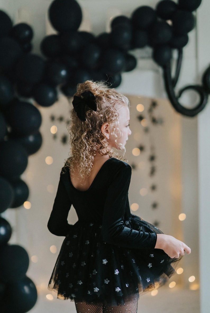 Child turned away revealing the deep scoop-back design of the midnight velvet bodysuit.