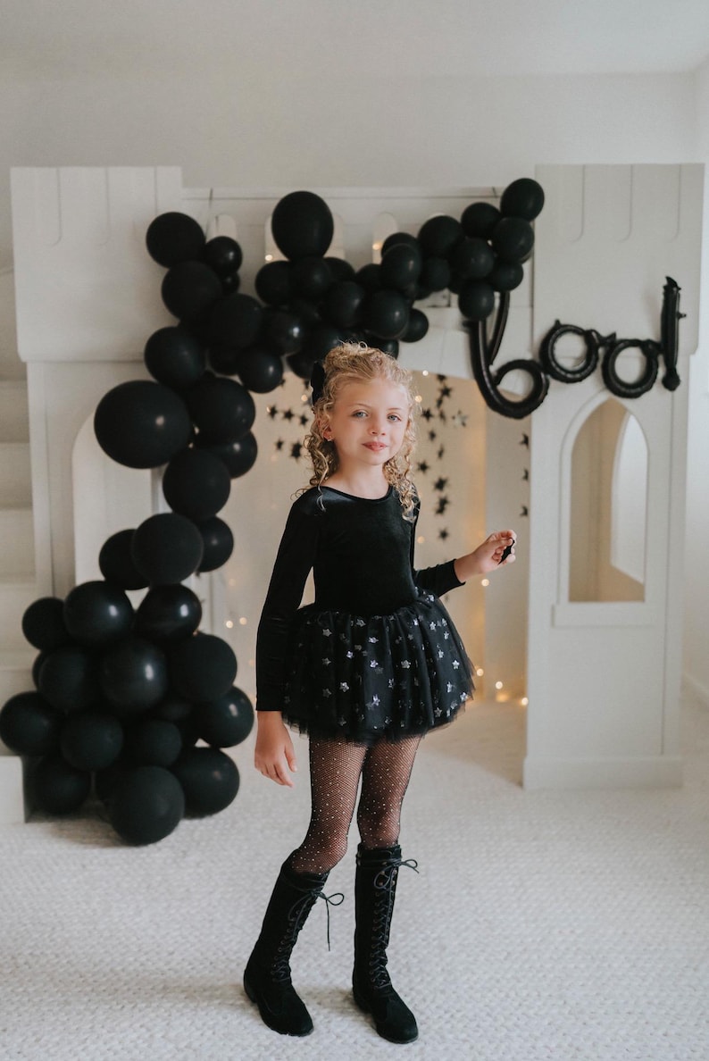 Child posing in a black velvet star-tulle tutu bodysuit under dramatic balloon décor.