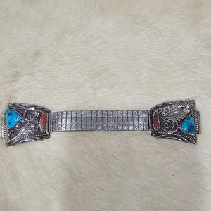 Könnte beinhalten: Ein silbernes Armband mit türkisfarbenen und korallenfarbenen Akzenten. Das Armband besteht aus einer Reihe kleiner, miteinander verbundener Metallteile.