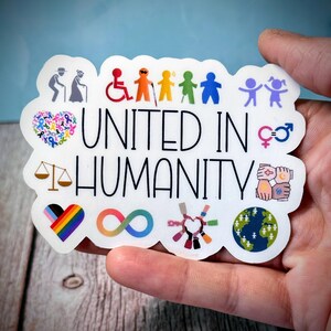 May include: A white sticker with the words "UNITED IN HUMANITY" in black. The sticker features various colorful symbols representing diversity, inclusion, and unity, including a rainbow heart, an infinity symbol, and figures representing different abilities.