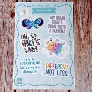 May include: A sheet of stickers with a light blue background and a decorative border. The stickers feature various designs, including a butterfly, a brain, and text that reads "Beautifully Wired," "My Brain Didn't Come With A Manual," and "Different Not Less."