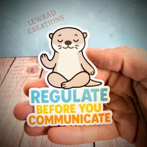 Puede incluir: Una pegatina troquelada que muestra una nutria de dibujos animados de color marr&oacute;n claro sentada en posici&oacute;n de meditaci&oacute;n con las piernas cruzadas y los ojos cerrados. Debajo, el texto dice REGULATE en azul, BEFORE YOU en amarillo y COMMUNICATE en naranja.